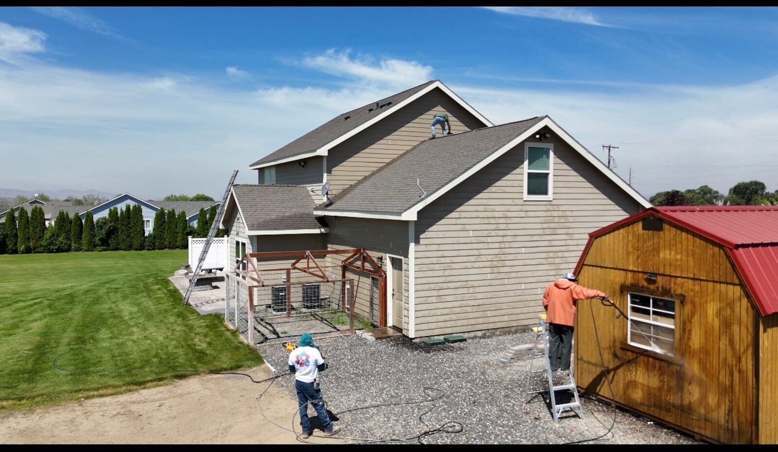 Crew spray-staining an outdoor shed